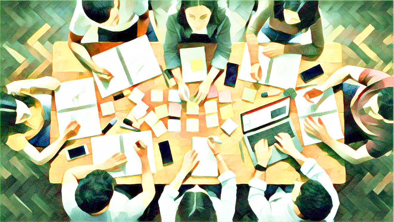 Teambesprechung um einen großen Tisch. Computer. Post-it.